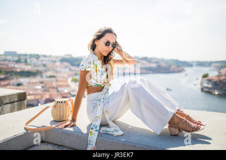 Junge Frau sitzt auf der Kante die Stadt Porto von oben beobachten Stockfoto