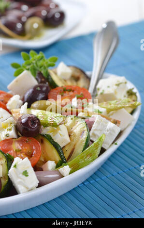 Griechische gebratenes Gemüse mit Feta-Käse und Kalamata Oliven, Fladenbrot im Hintergrund Stockfoto