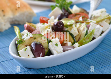 Griechische gebratenes Gemüse mit Feta-Käse und Kalamata Oliven, Fladenbrot im Hintergrund Stockfoto