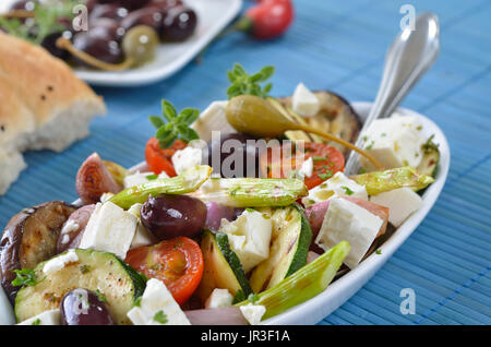 Griechische gebratenes Gemüse mit Feta-Käse und Kalamata Oliven, Fladenbrot im Hintergrund Stockfoto