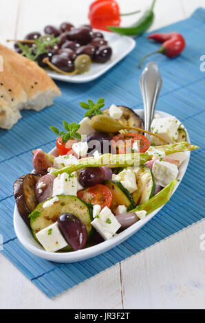 Griechische gebratenes Gemüse mit Feta-Käse und Kalamata Oliven, Fladenbrot im Hintergrund Stockfoto