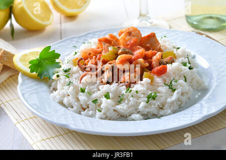 Meeresfrüchte-Ragout mit Basmati-Reis, Weißwein und Zitronen im Hintergrund Stockfoto