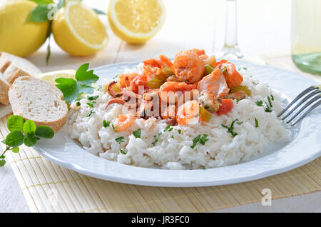 Meeresfrüchte-Ragout mit Basmati-Reis, Weißwein und Zitronen im Hintergrund Stockfoto