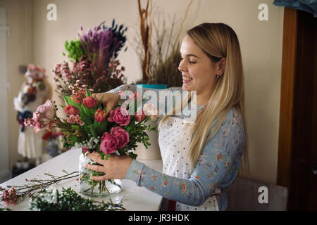 Frau Florist Blumenstrauss indoor machen. Weibliche Vorbereitung Blumenstrauß mit Rosen, Tulpen im Blumenladen Blumengeschäft Stockfoto