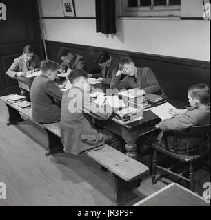 1948, England, UK, historische Bild zeigt eine Gruppe von Jungen in Jacke und Krawatte tun ther prep oder nach dem Unterricht Hausaufgaben gemeinsam an einem Tisch in Haileybury Publlic Schule, eine traditionelle englische Knabeninternat. Stockfoto