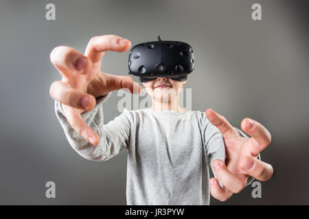 Mädchen tragen virtual-Reality Brille auf grauem Hintergrund. VR-Brille. 360 Grad. Virtual-Reality-Kopfhörer. VR-Spiel. Tragen von virtual-Reality-g Stockfoto