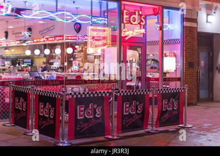 Eine einsame Kundin ein Kopftuch, sitzen in einem hell erleuchteten Diner genannt "EDS" im Stadtzentrum von Canterbury am frühen Abend. Stockfoto