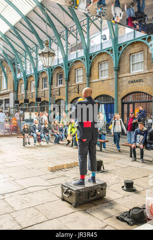 Eine street Entertainer Durchführung innerhalb des berühmten Covent Garden, London, UK, vor einer Masse von Erwachsenen und Kindern. Stockfoto