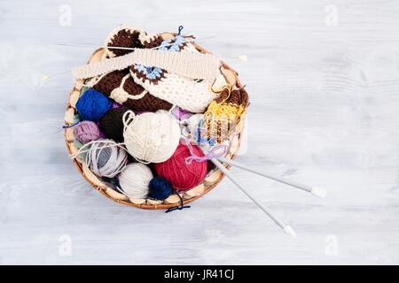 Bunte Wolle Kugeln und Nadeln in hölzernen Korb. Wolle stricken Stockfoto