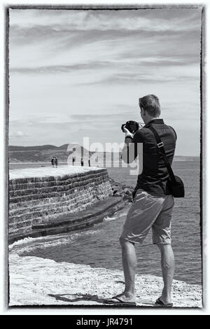 Mann Fotograf unter Fotos Fotos von Besuchern auf The Cobb bei Lyme Regis, Dorset im Juli Stockfoto