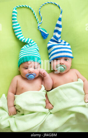 Zwillinge-Brüder-Babys weared in gestreiften Hüte gebunden auswendig. Stockfoto