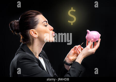 Geschäftsfrau Fütterung piggy Bank Stockfoto