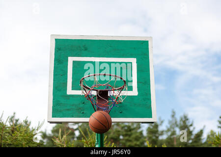 Der Basketballkorb im Garten. Ball wird Trown in den Reifen. Stockfoto