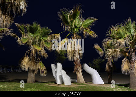 Eine Statue von einem offenen Hand mit einem Palmen direkt am Strand in Fuengirola ist in der Nacht beleuchtet Stockfoto