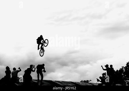 Extreme Radfahrer, junge Mann tut einen Sprung mit einem bmx-Bike auf dem Hintergrund der schwarzen und weißen Silhouette und Wolken Stockfoto