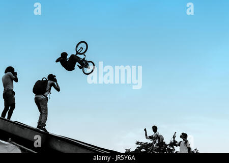 Extreme Radfahrer, junger Mann, einen Sprung mit einem bmx-Bike auf dem Hintergrund des blauen Himmels zu tun. Mit Platz für Ihren Text zur Nutzung im Hintergrund. Stockfoto