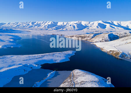 Ice am Rande fällt Dam, und Hawkdun im Winter, Maniototo, Central Otago, Südinsel, Neuseeland - Luftbild Drohne Stockfoto