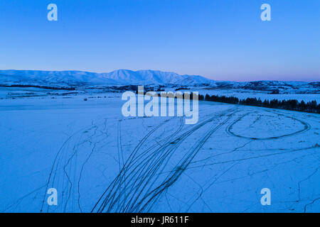 Schafe Essen Winterfutter, drone, Hawkdun Bereich und verschneiten Ackerland in der Nähe von Oturehua, Maniototo, Central Otago, Südinsel, Neuseeland - Antenne Stockfoto