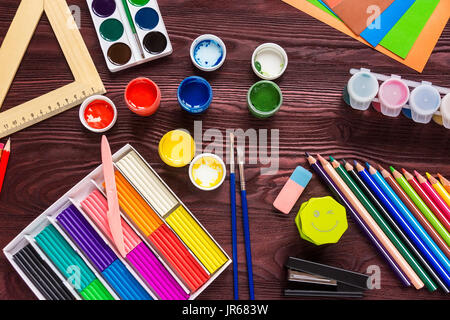 Schule-Versorgungsmaterialien auf einem roten Hintergrund, Farben und Pinsel Stockfoto