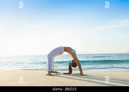 Frau tun, Rad-Yoga-Pose am Strand, Bali, Indonesien Stockfoto