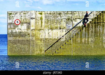 Junge im Neoprenanzug Hafen Stufen Cullercoats ausgeführt Stockfoto