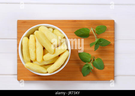 Schüssel mit gekochten Kartoffeln Kegel oder Gnocchi auf Holzbrett Stockfoto