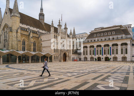 Eine einsame Frau geht über den Platz in der Guildhall in London, England Stockfoto