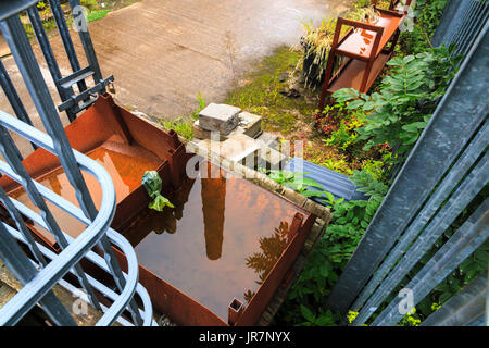 Reflexion eines Schornsteins Mühle in redundante Ausrüstung in einem verlassenen Hof in Hebden Bridge, West Yorkshire, Großbritannien Stockfoto