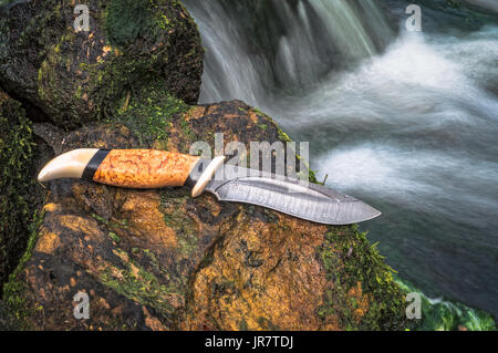 Damaskus Messer liegen auf dem Stein in der Nähe des Flusses. Stockfoto