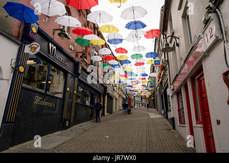 Menschen zu Fuß durch die Straße in Enniscorthy, Irland mit schwebenden Sonnenschirme für den Rockin' Food Festival eingerichtet Stockfoto