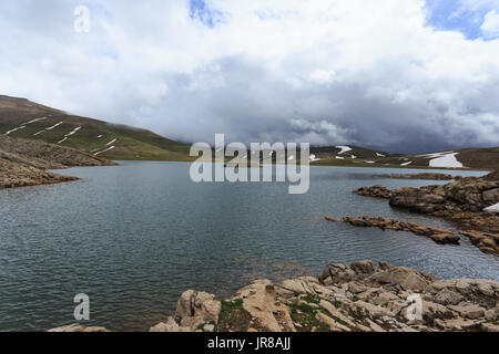 Horizontalen Schuss von Mountain Lake umgeben von Pisten fallenden Schnee schmelzen Stockfoto