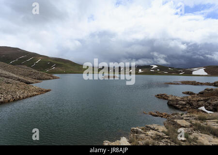 Horizontalen Schuss von Mountain Lake umgeben von Pisten fallenden Schnee schmelzen Stockfoto