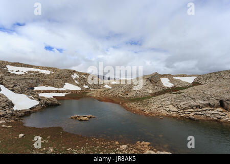 Horizontalen Schuss von Mountain Lake umgeben von Pisten fallenden Schnee schmelzen Stockfoto
