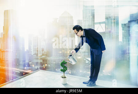 Man gießt Wasser auf Dollar geprägt. Das geschäftliche Wachstum und unternehmerische Initiative Konzept. Stockfoto