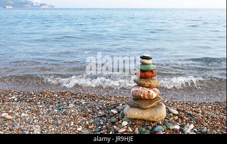 Steinen Gleichgewicht am Strand bei Sonnenuntergang. Konzept des Friedens und der Harmonie. Stockfoto