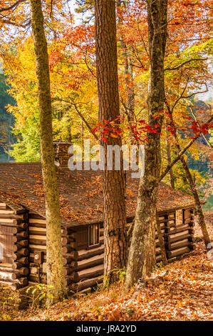 Am Seeufer Blockhaus (erbaut durch das Civilian Conservation Corps in den 1930er Jahren) unter einem bunten Spektrum an Herbst Blätter im Georgiens Vogel State Park. Stockfoto