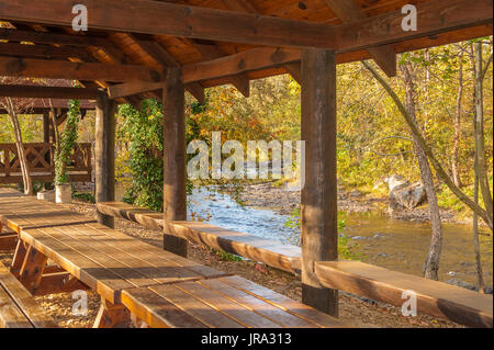 Creekside Picknickschutz auf dem friedlichen Chattahoochee River an einem Herbstabend bei Sonnenuntergang in Helen, Georgia. (USA) Stockfoto