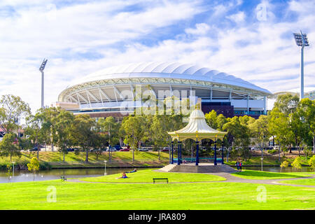 Adelaide, Australien - 2. Dezember 2017: Menschen entspannen in der Nähe von Elder Park Rotunde mit Adelaide Oval auf dem Hintergrund an einem warmen Sommertag Stockfoto