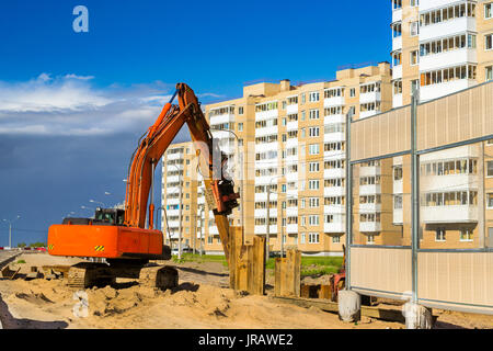 Kettenbagger zu Hammer ein Stahlträger in den Boden. Bau der Umgehungsstraße um Krassnoje Selo, Sankt Petersburg. Schwere Maschine equ Stockfoto