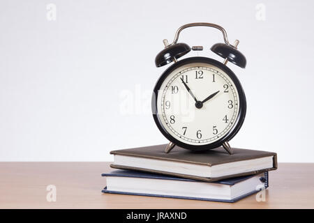 Wecker steht auf zwei Bücher vor weißem Hintergrund Stockfoto