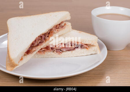 Sandwich mit Fleisch in der Hälfte liegen auf dem Teller von Tasse Kaffee Stockfoto