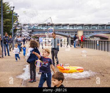 Straße Entertainer Hereinholen Tipps unterhalten Kinder durch Einblasen große bunte Luftblasen, Bankside, Böschung, South Bank, London SE1, UK Stockfoto