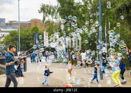 Straße Entertainer Hereinholen Tipps unterhalten Kinder durch Einblasen große bunte Luftblasen, Bankside, Böschung, South Bank, London SE1, UK Stockfoto