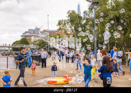 Straße Entertainer Hereinholen Tipps unterhalten Kinder durch Einblasen große bunte Luftblasen, Bankside, Böschung, South Bank, London SE1, UK Stockfoto