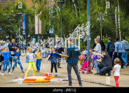 Straße Entertainer Hereinholen Tipps unterhalten Kinder durch Einblasen große bunte Luftblasen, Bankside, Böschung, South Bank, London SE1, UK Stockfoto