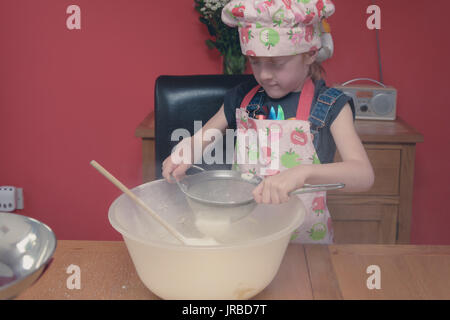 Kleines Mädchen Plätzchen backen in einem niedlichen rosa Köche Hut und Schürze Stockfoto