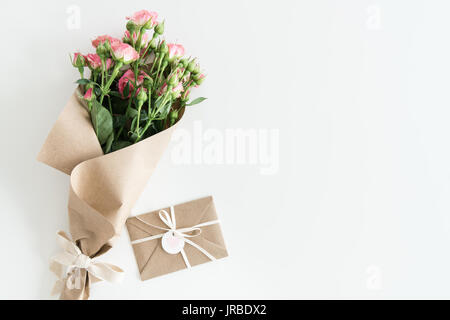 Rosa Rosen in Kraftpapier und Umschlag isoliert auf weiss mit Textfreiraum, Hochzeit Karten Blumen Konzept Stockfoto