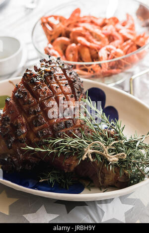 Köstliche Australische Weihnachten verglaste Abendessen Schinken mit Rosmarin und frische Garnelen im Hintergrund. Stockfoto