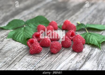 Frische und reife Himbeeren auf einem hölzernen Hintergrund. Stockfoto