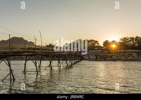 Holzbrücke über Nam Song River während des Sonnenuntergangs im Dorf Vang Vieng, Laos Stockfoto